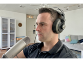 Andrew Dean with headphones and a microphone, preparing to record a podcast episode.